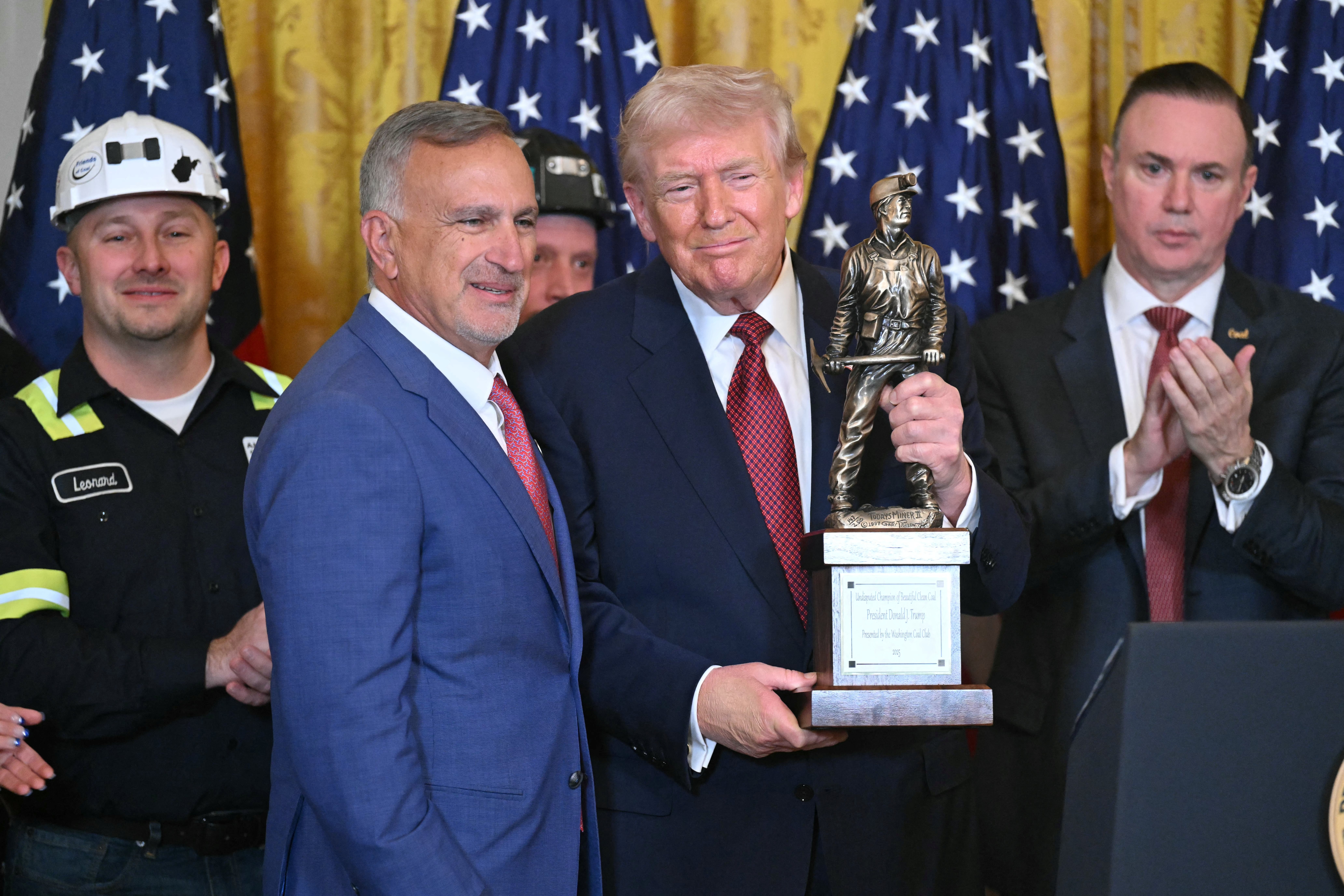 A radical of men basal indoors, 1 holding a trophy shaped similar a worker. American flags are successful the background
