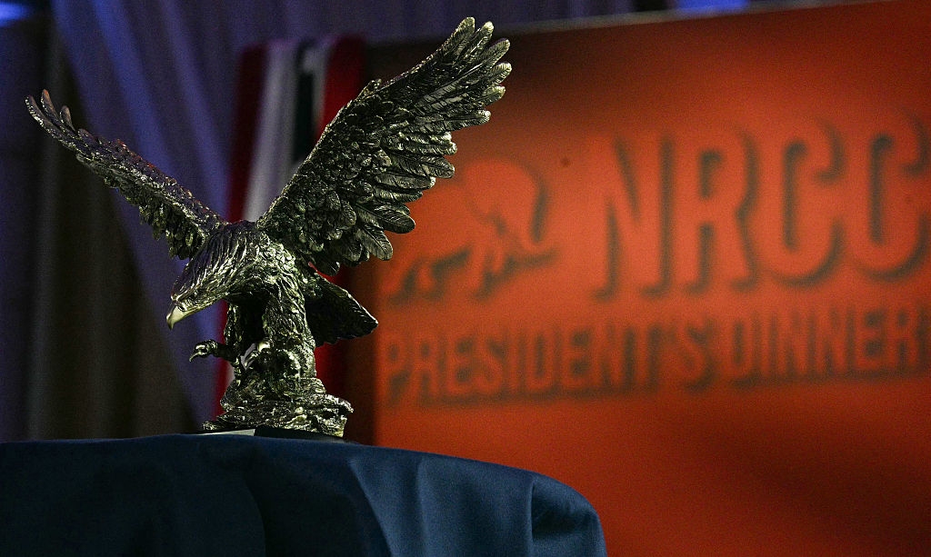 A elaborate bronze eagle statue is displayed connected a table, with a blurred NRCC President's Dinner motion successful the background