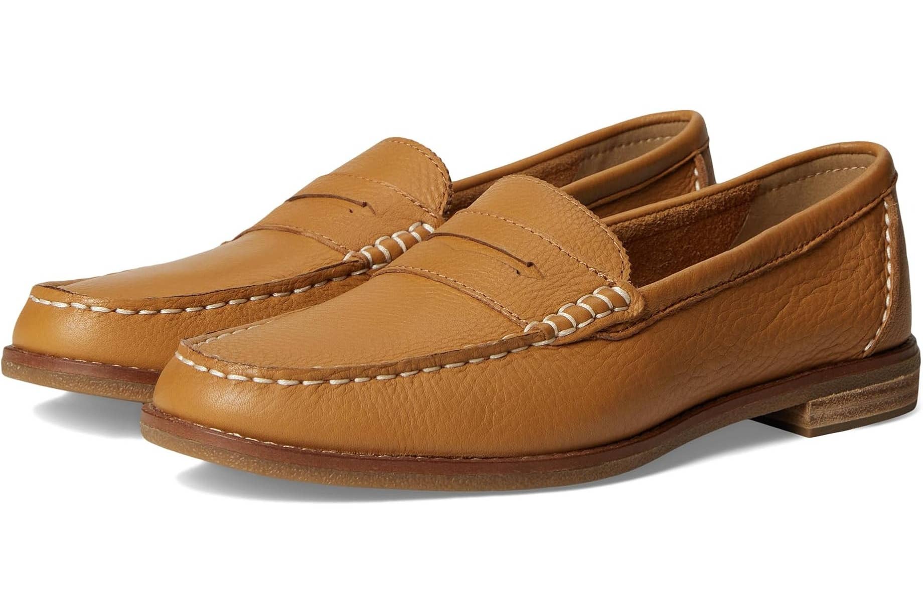 A pair of Sperry tan leather penny loafers with stitching detail and stacked wooden soles, displayed at an angle