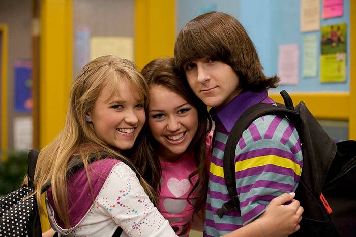 Three young radical   smiling and hugging successful  a schoolhouse  setting, wearing casual outfits with backpacks