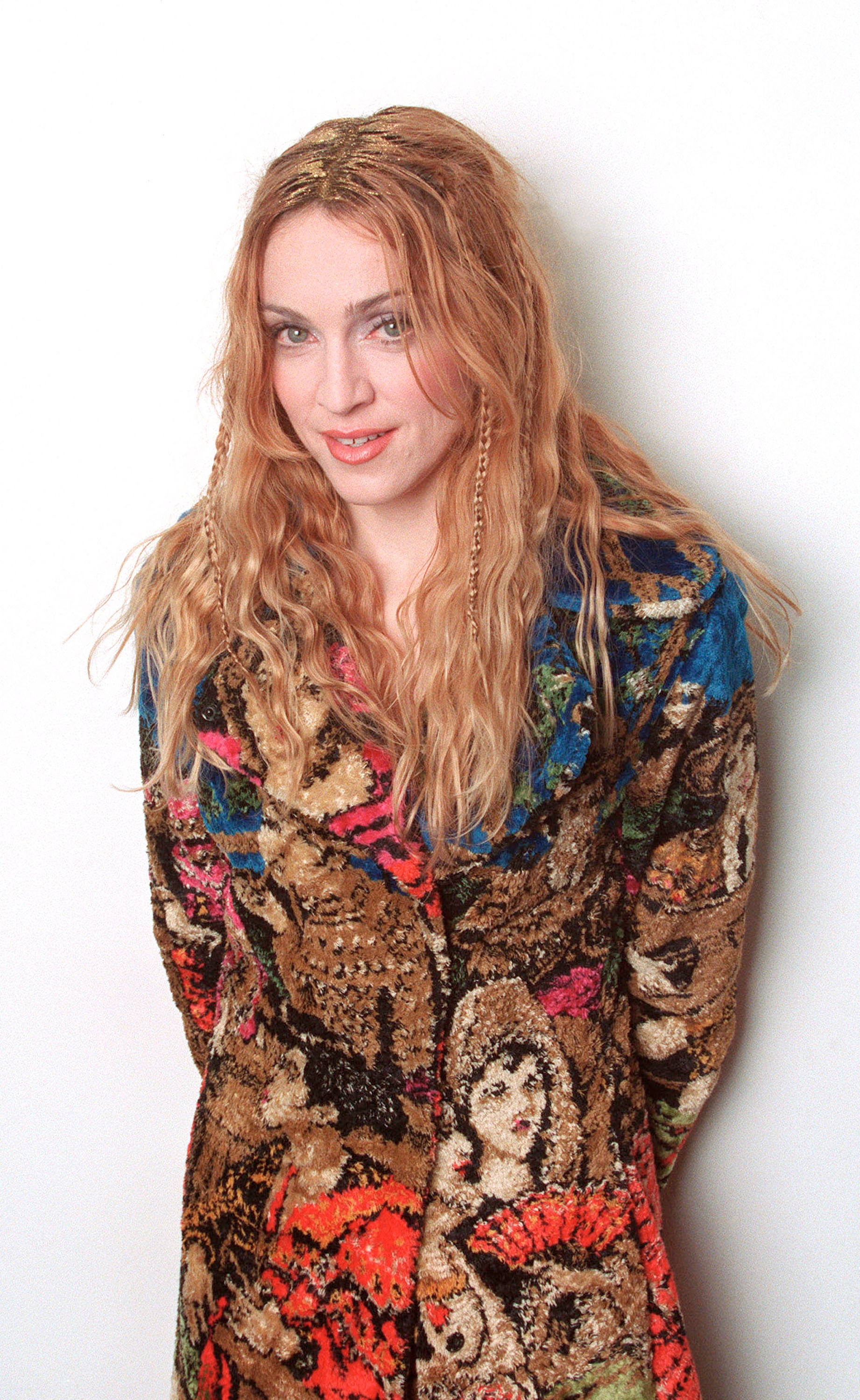 A idiosyncratic   with long, wavy hairsbreadth  is wearing a richly patterned overgarment  featuring creator  designs