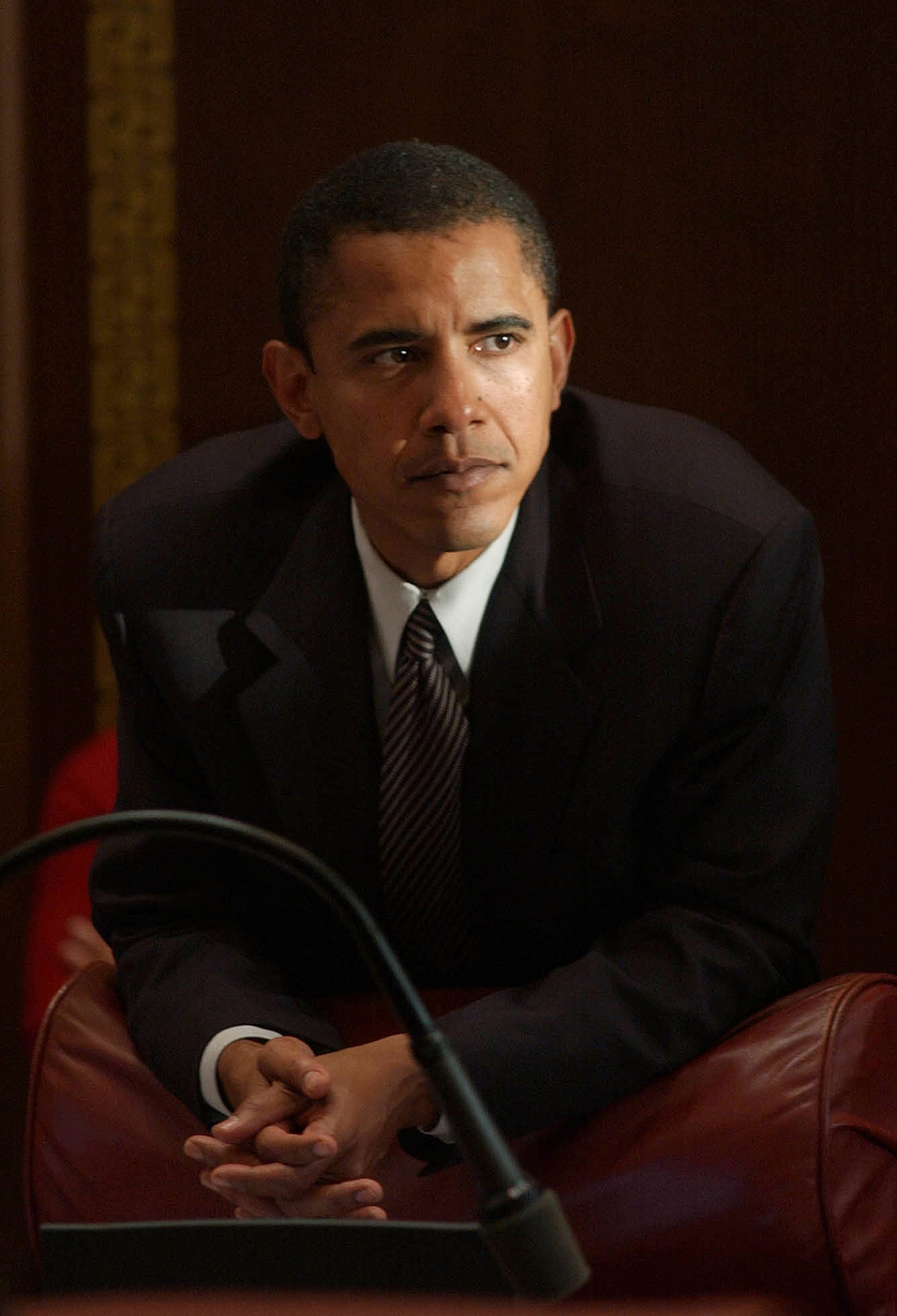 A idiosyncratic   successful  a ceremonial  suit   is leaning connected  a seat  with a thoughtful expression, perchance  astatine  a nationalist   lawsuit   oregon  meeting