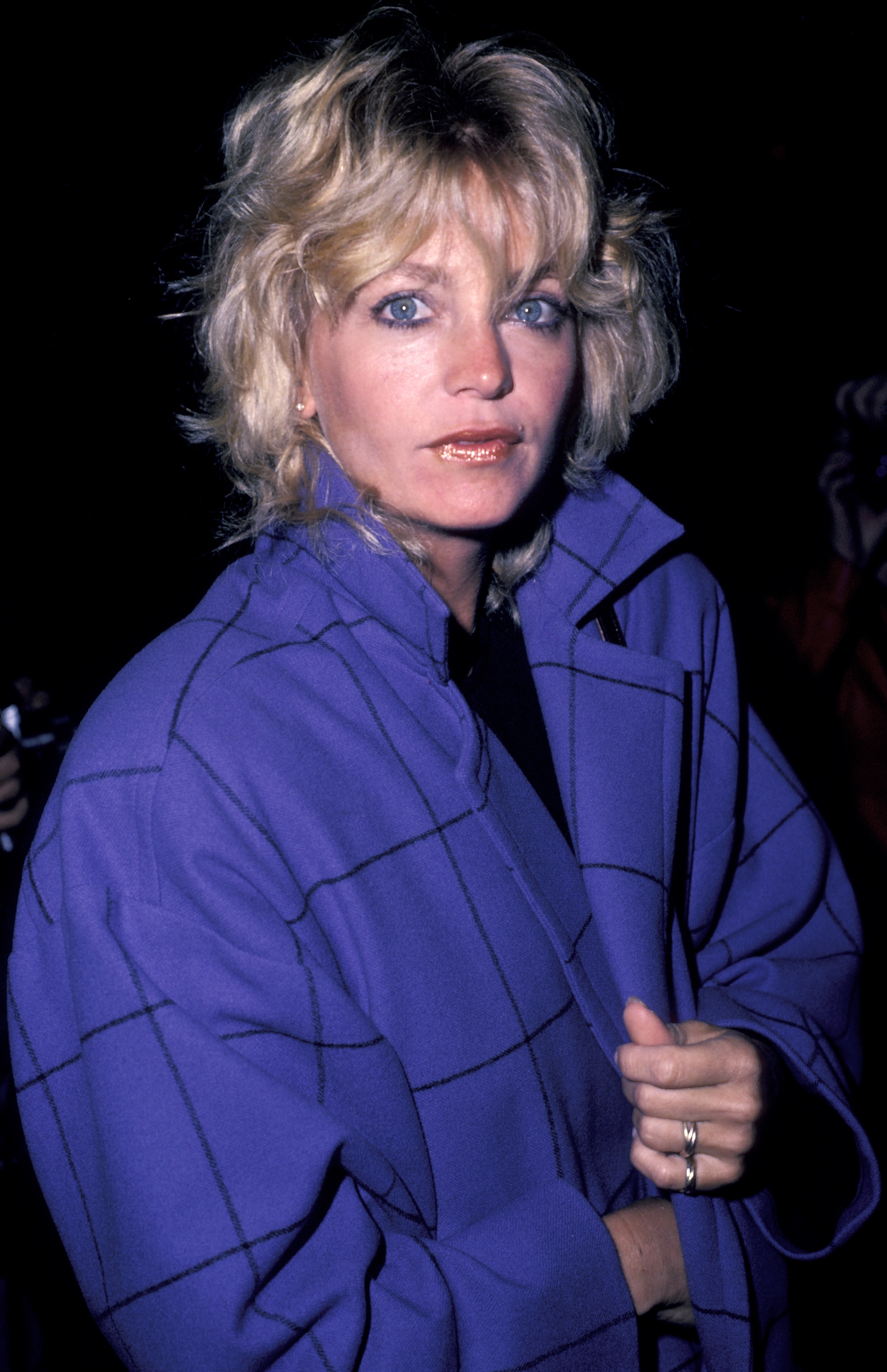 Person successful  a checkered overgarment  attending an event. They person  short, wavy hairsbreadth  and are looking astatine  the camera