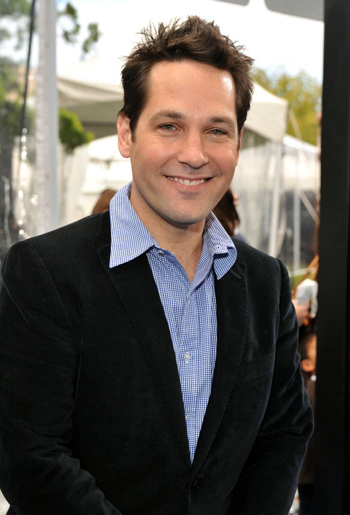 Person successful  a blazer and checkered garment  smiles astatine  an outdoor event