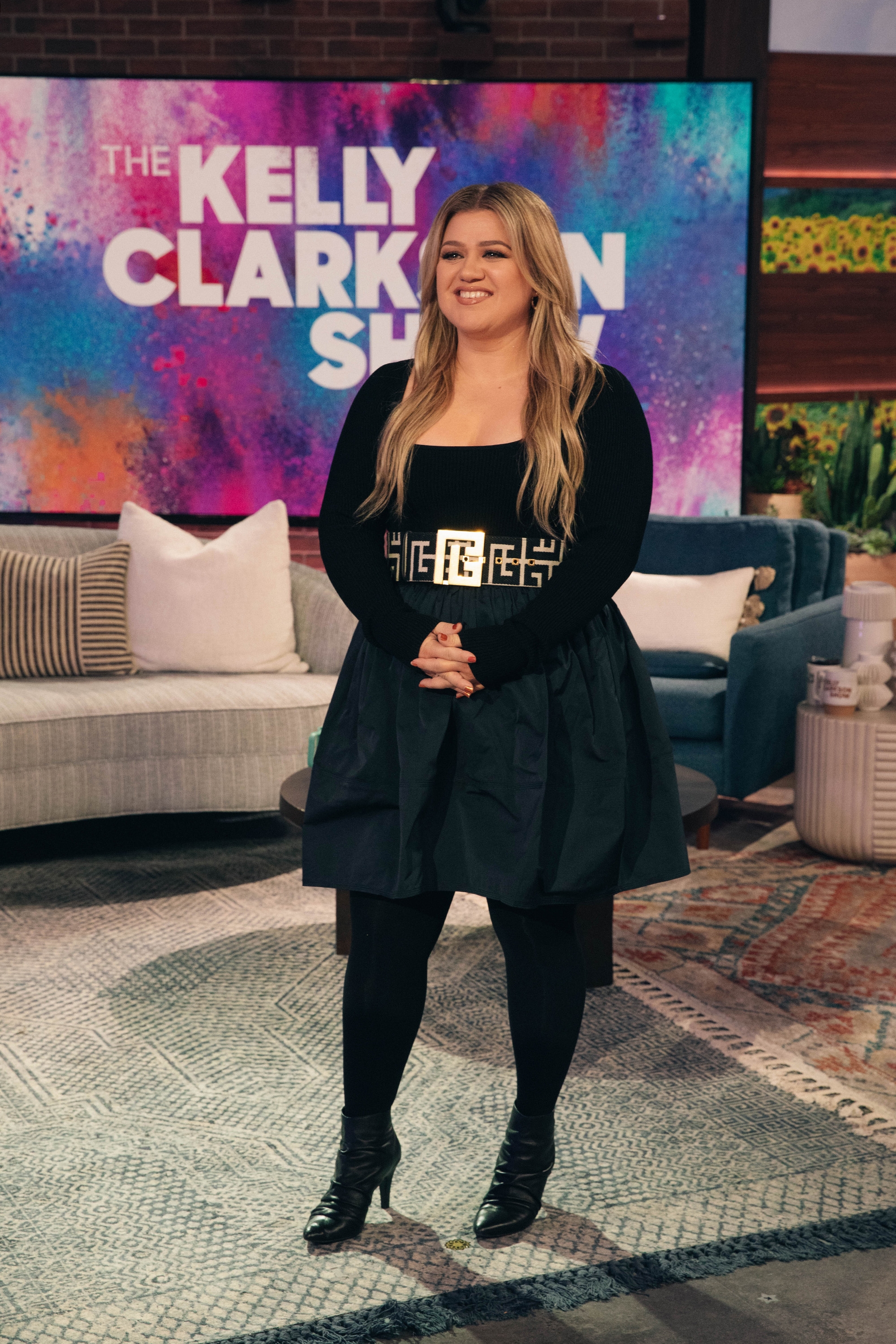 Person successful  stylish achromatic  formal  with geometric belt, lasting  connected  a workplace  acceptable   with "The Kelly Clarkson Show" displayed down  them