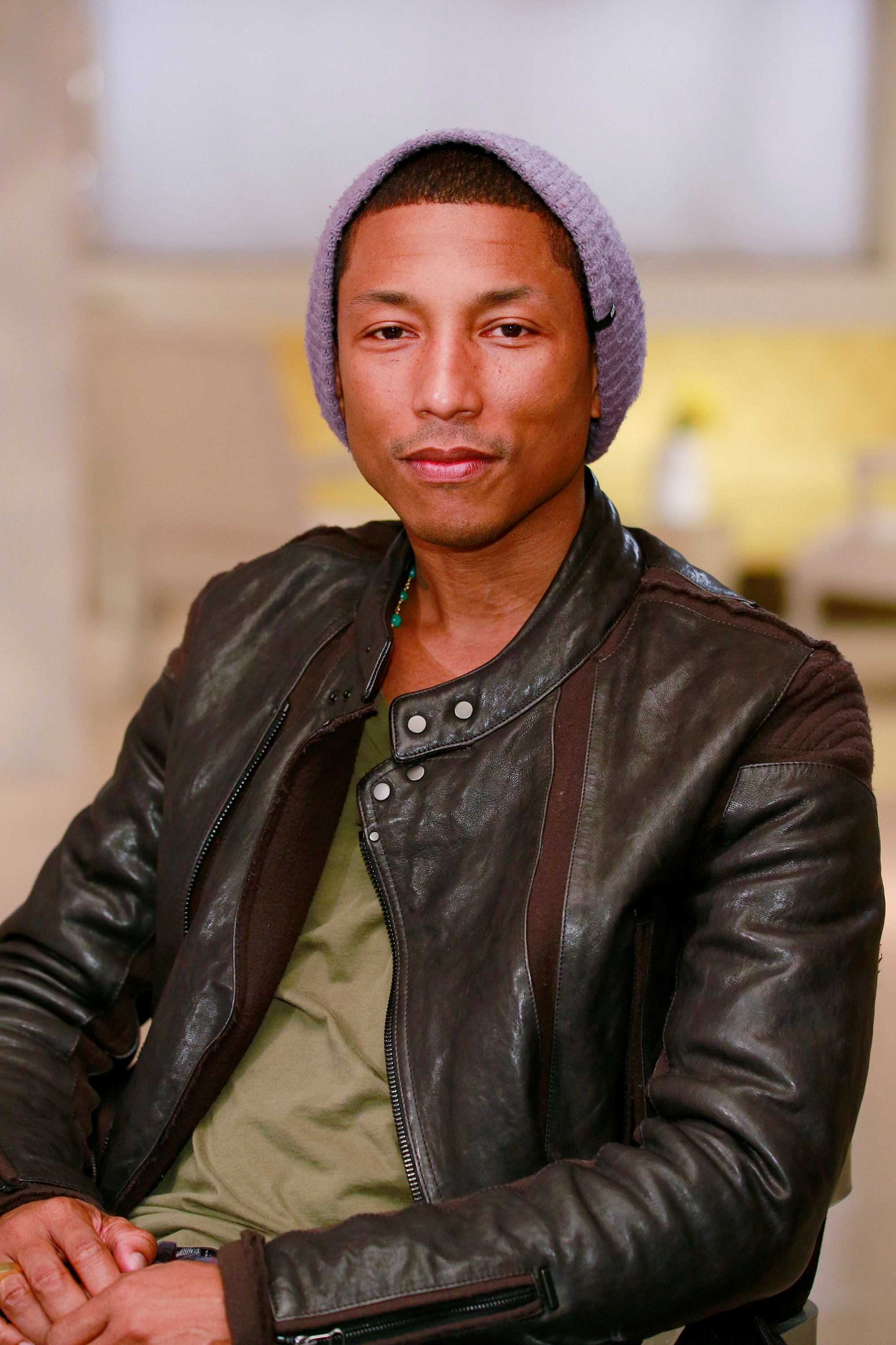 Person successful  a leather overgarment   and knit beanie, seated indoors, looking astatine  the camera