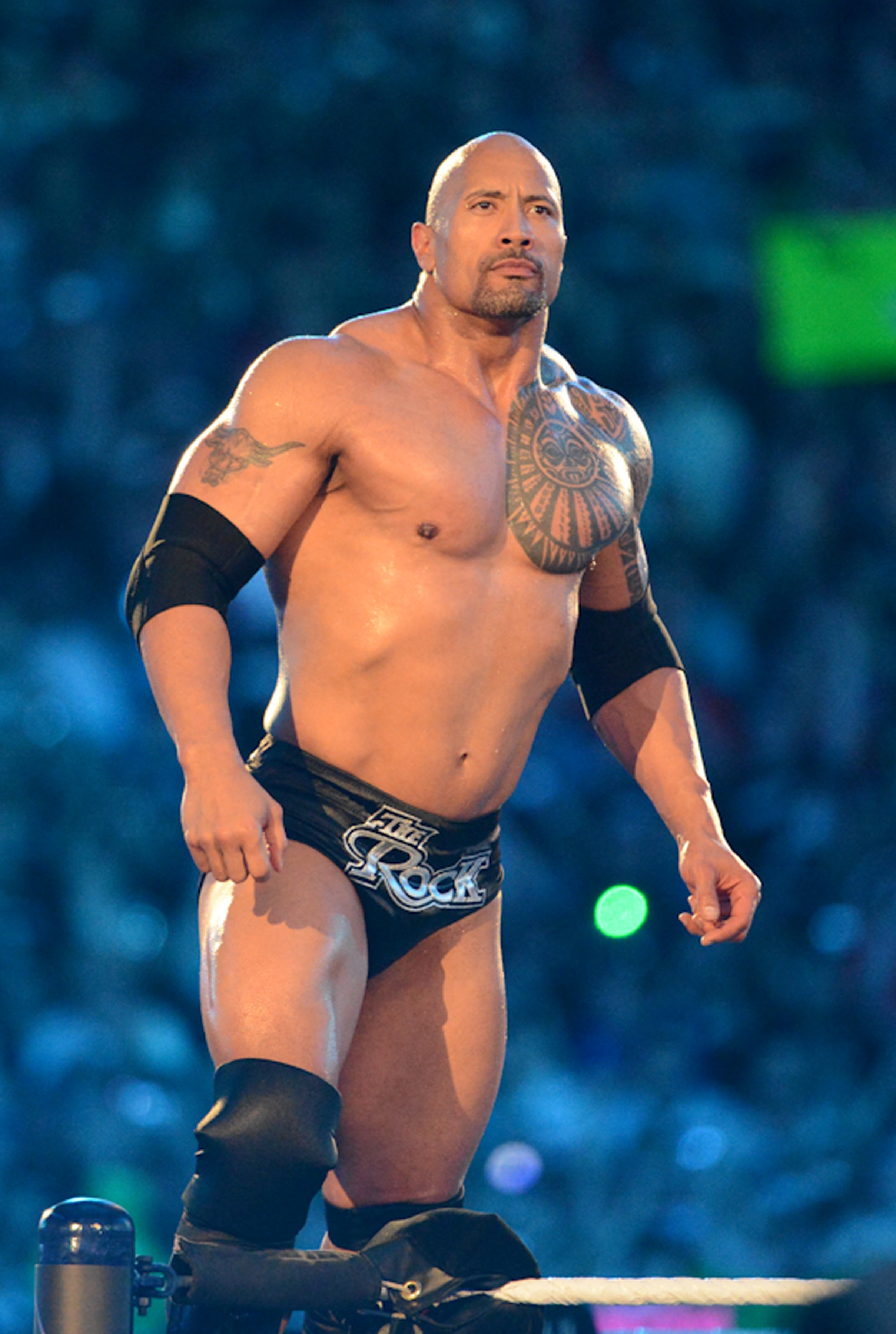 A muscular antheral   successful  wrestling attire stands confidently successful  a ring, showcasing tattoos and genu  pads, during a nationalist   wrestling event