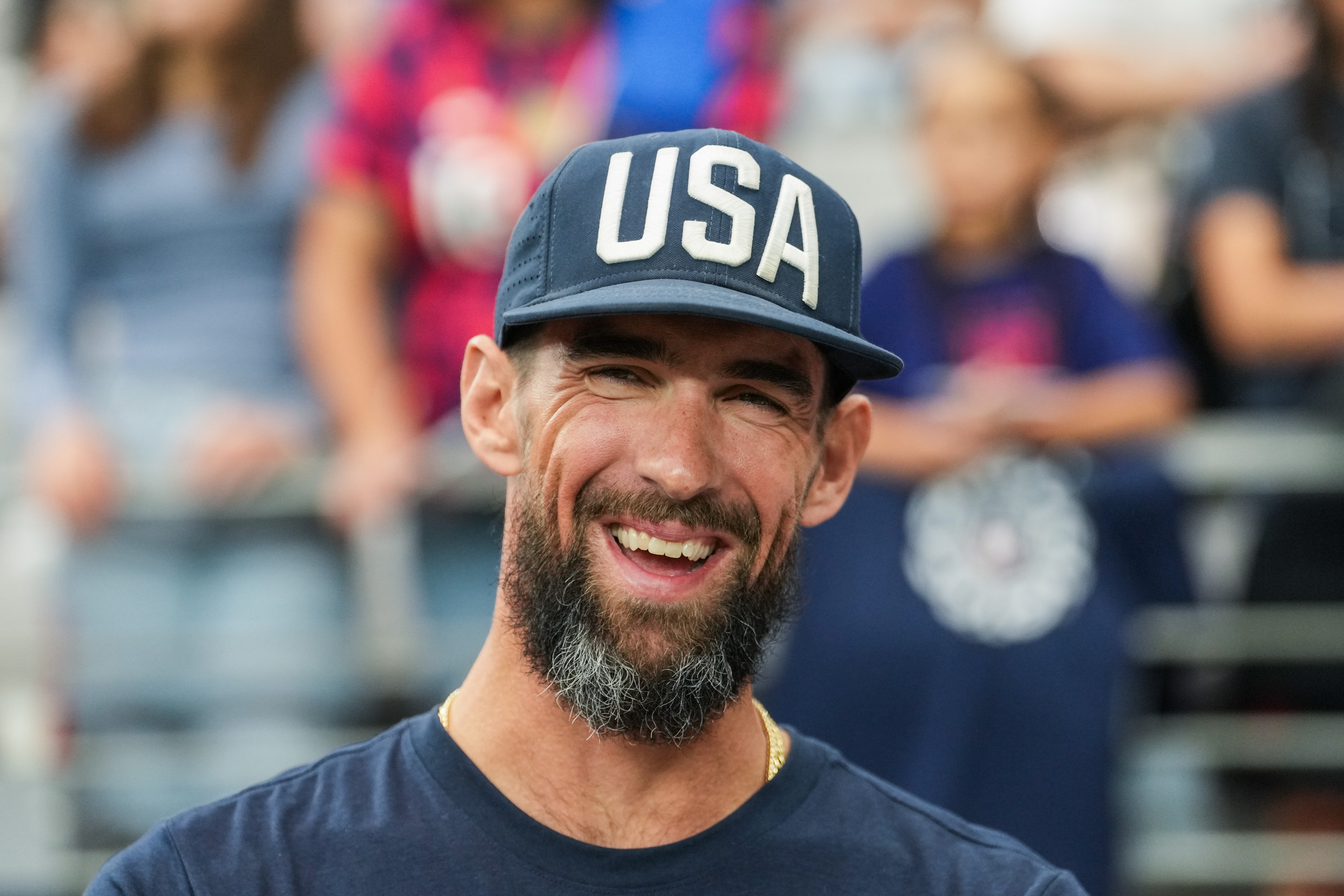 Person wearing a "USA" headdress  and shirt, smiling astatine  an outdoor event