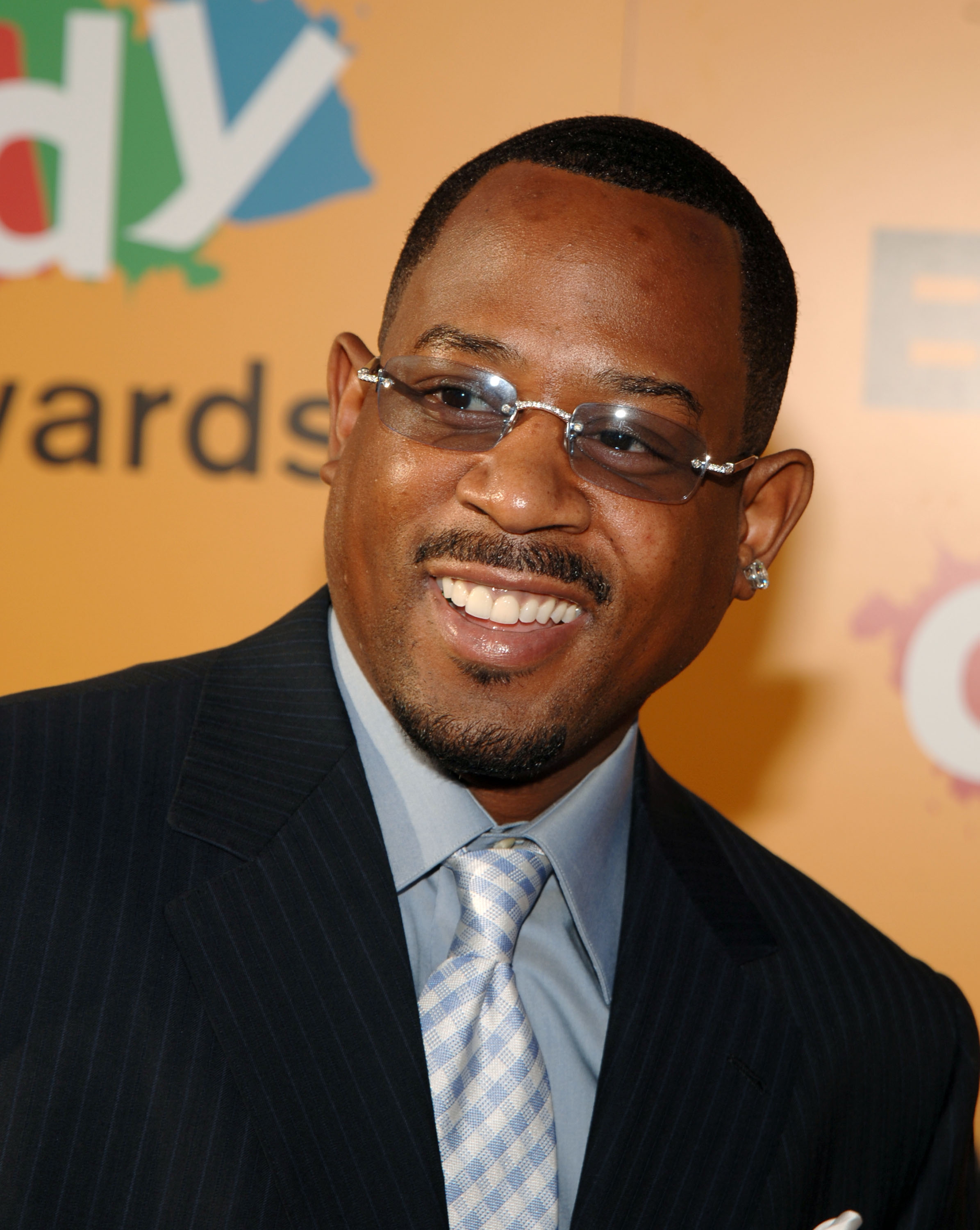 Man successful  suit   with necktie  and glasses, smiling astatine  an lawsuit   backdrop