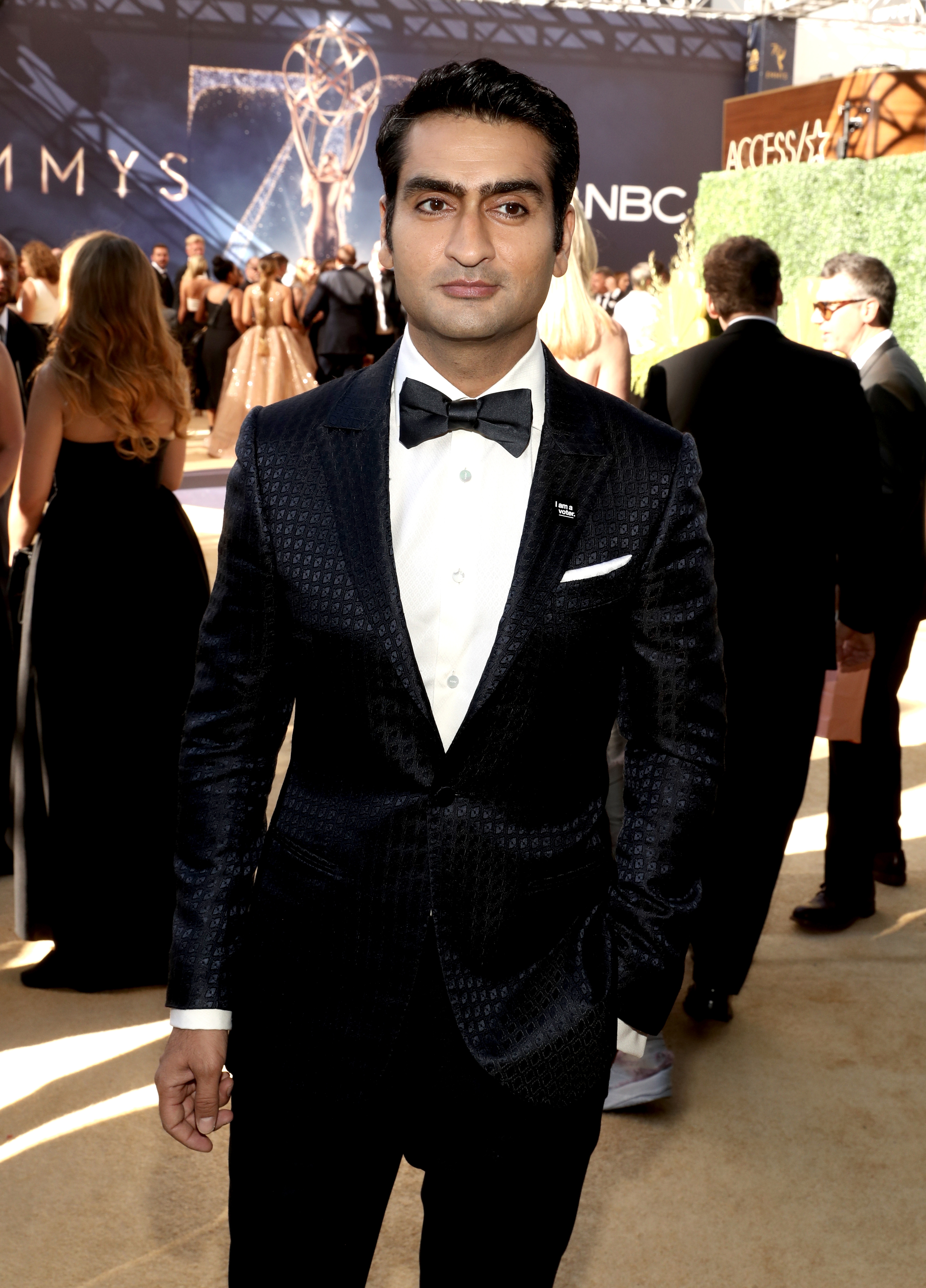 Man successful  a ceremonial  achromatic  suit   with a bow necktie  posing connected  a reddish  carpet astatine  an awards event