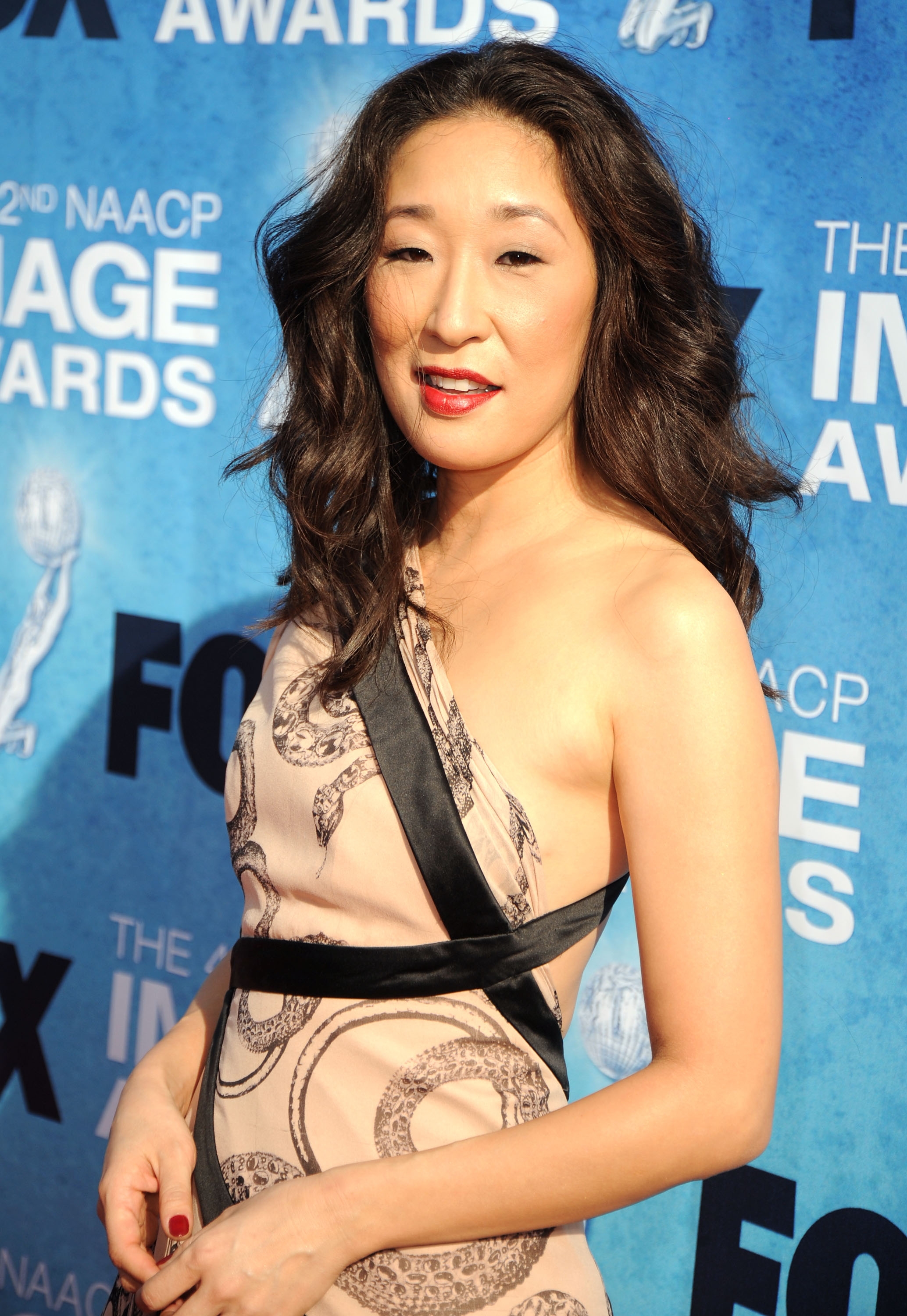 Person successful  an elegant one-shoulder formal  with achromatic  accents, posing connected  a bluish  carpet astatine  a personage  lawsuit   backdrop