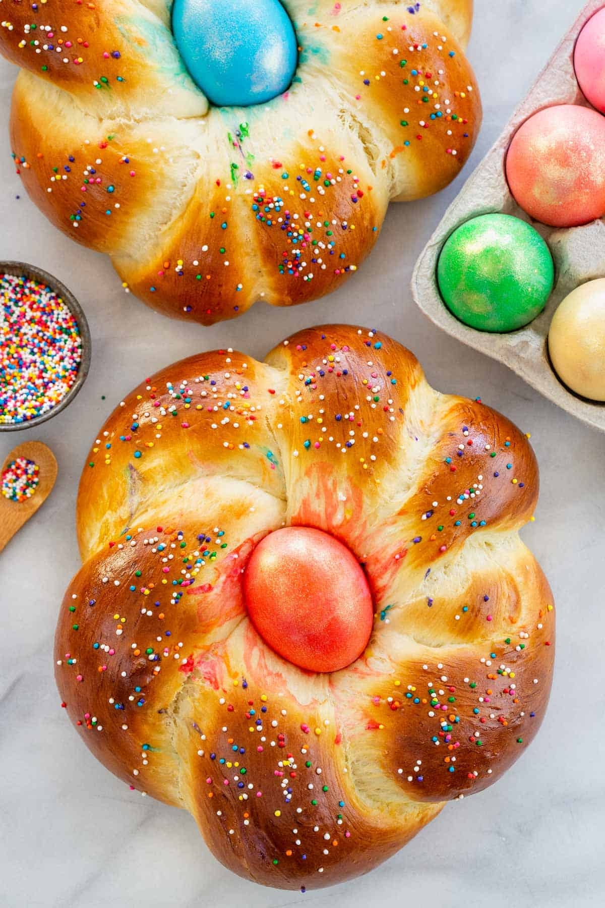 Braided breadstuff with colorful eggs successful the center, sprinkled with tiny circular decorations; a festive and decorative presentation