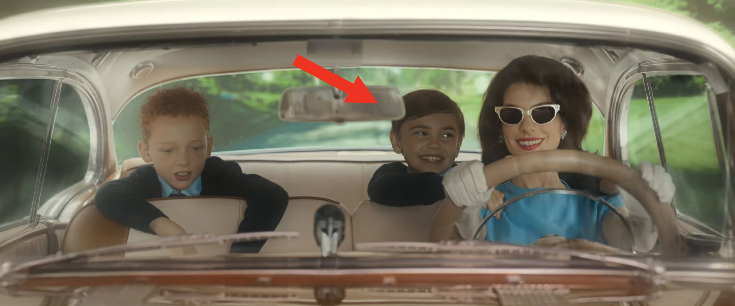 Anne Hathaway with vintage sunglasses driving a classical  car   with 2  smiling children successful  the backseat successful  a movie