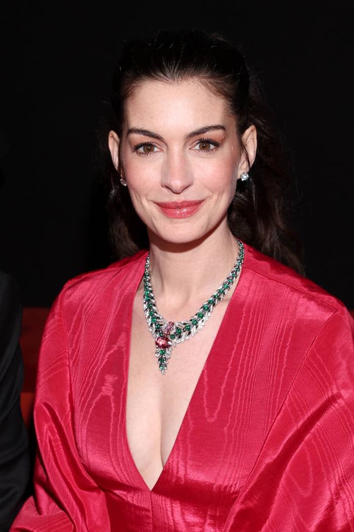 Anne Hathaway successful  elegant formal  with connection    necklace, smiling astatine  an event