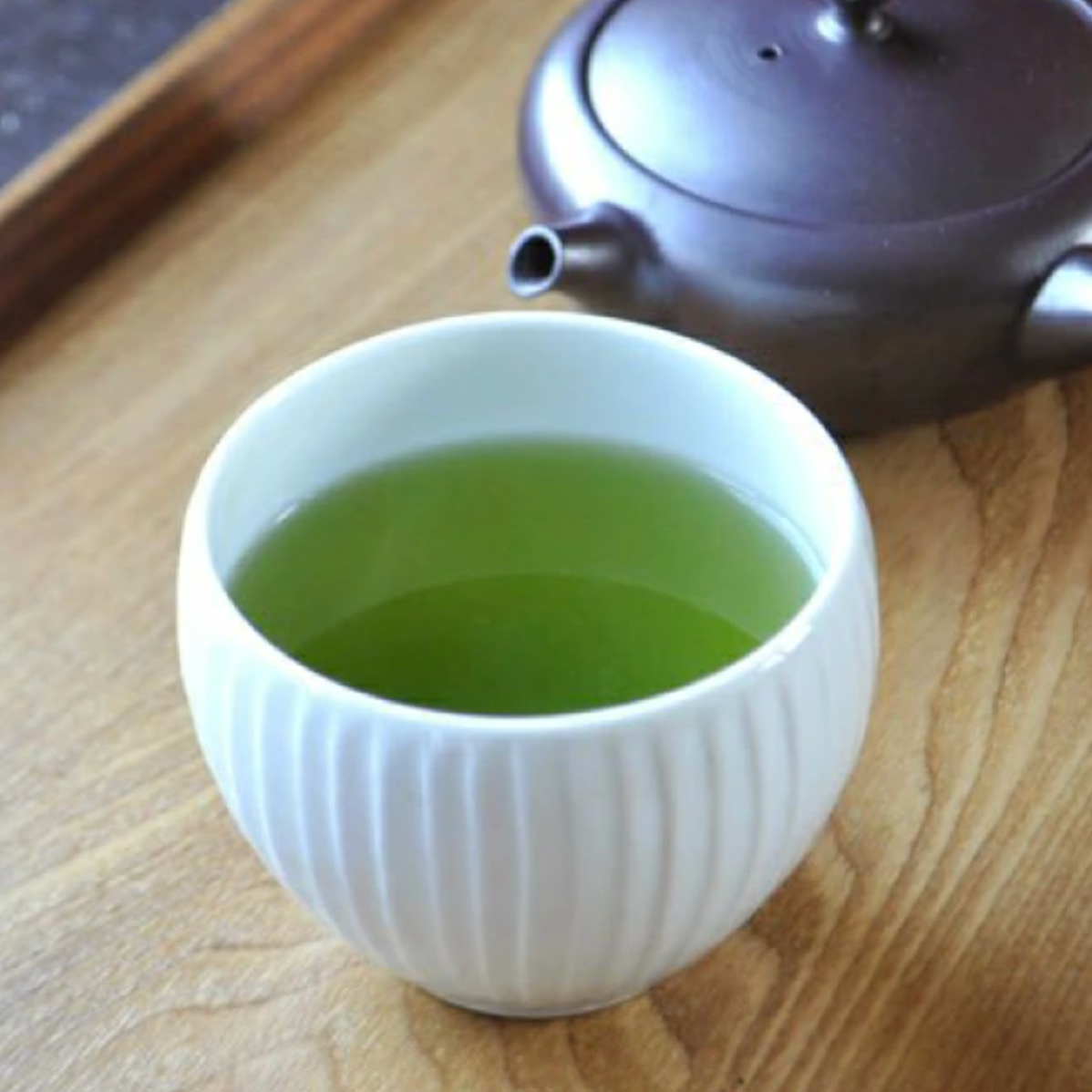 テーブルに置かれた湯飲みの中に、温かい緑茶が注がれている。隣に急須が見える。