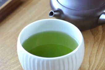 テーブルに置かれた湯飲みの中に、温かい緑茶が注がれている。隣に急須が見える。