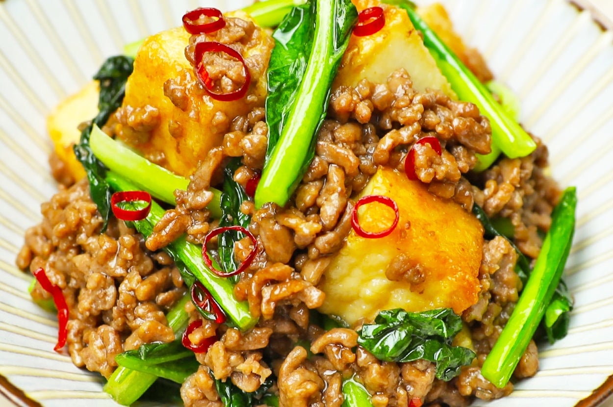 皿に盛られた肉と野菜の炒め物。パプリカらしき赤い輪切りの野菜がトッピング。