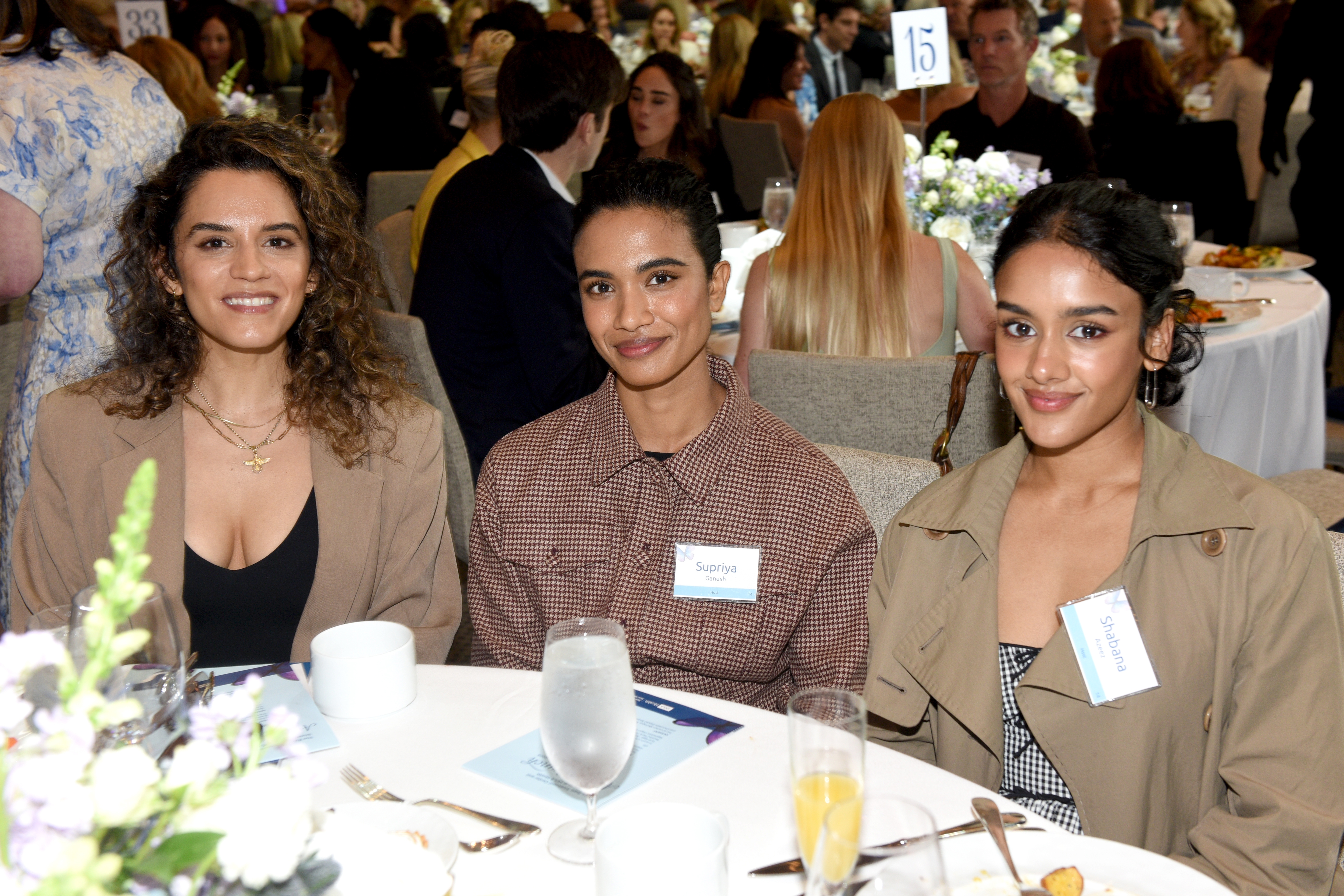 Three radical   grin  astatine  a ceremonial  event, seated astatine  a array  with sanction  tags and drinks