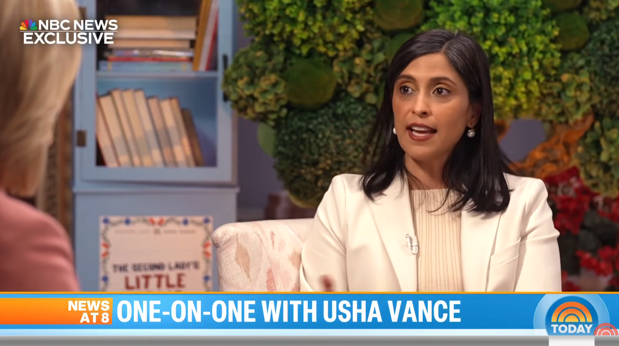 A pistillate successful a achromatic blazer sits for a one-on-one interrogation connected NBC News. A support with books is disposable successful the background