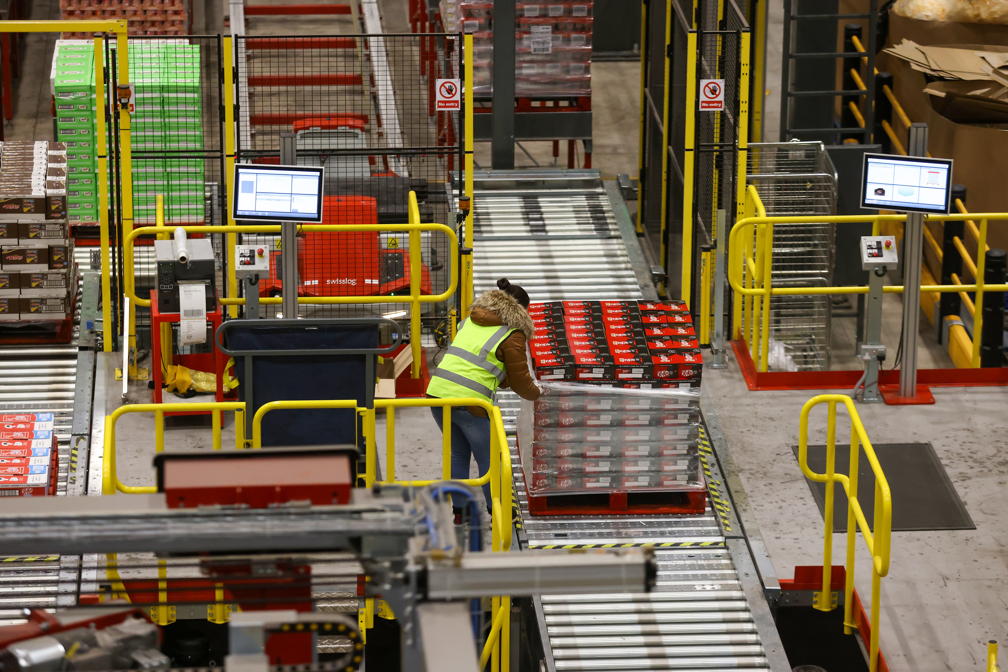 Person successful information vest arranging nutrient packages successful a warehouse with conveyor belts and monitors, focusing connected organized nutrient distribution