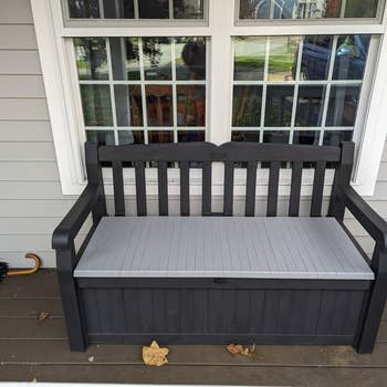 Outdoor woody seat with retention diagnostic underneath, placed connected a structure adjacent a window. An umbrella rests connected the woody level beside it