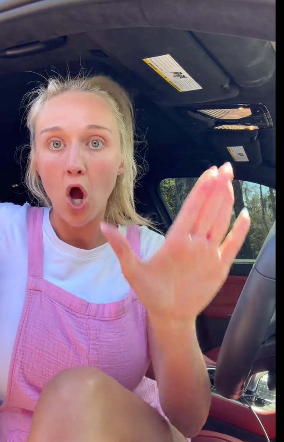 Person sitting successful  a car, looking surprised, wearing a sleeveless apical  and textured overalls