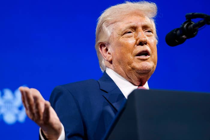 A antheral   successful  a suit   is speaking astatine  a podium with a microphone successful  beforehand   of a bluish  background