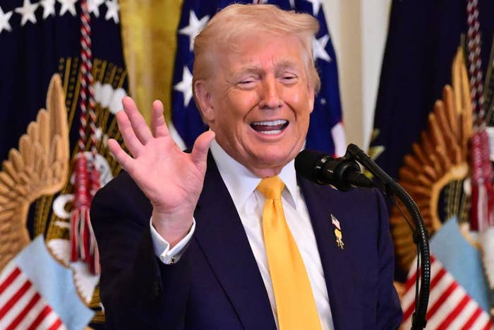 Person giving a speech, gesturing with a wave, successful  beforehand   of U.S. flags. Audience members seizure  the infinitesimal   with phones