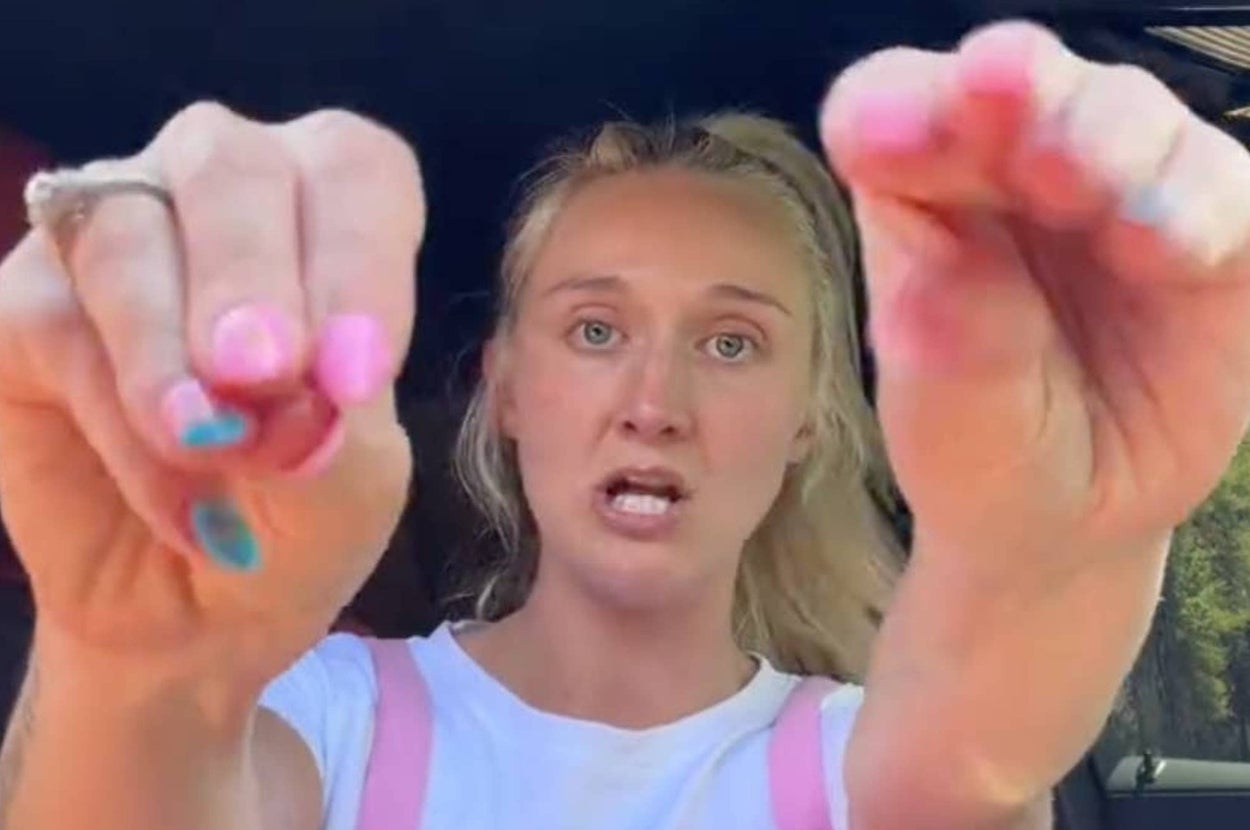 Person with long nails of different colors gestures towards the camera, appearing to explain or emphasize something