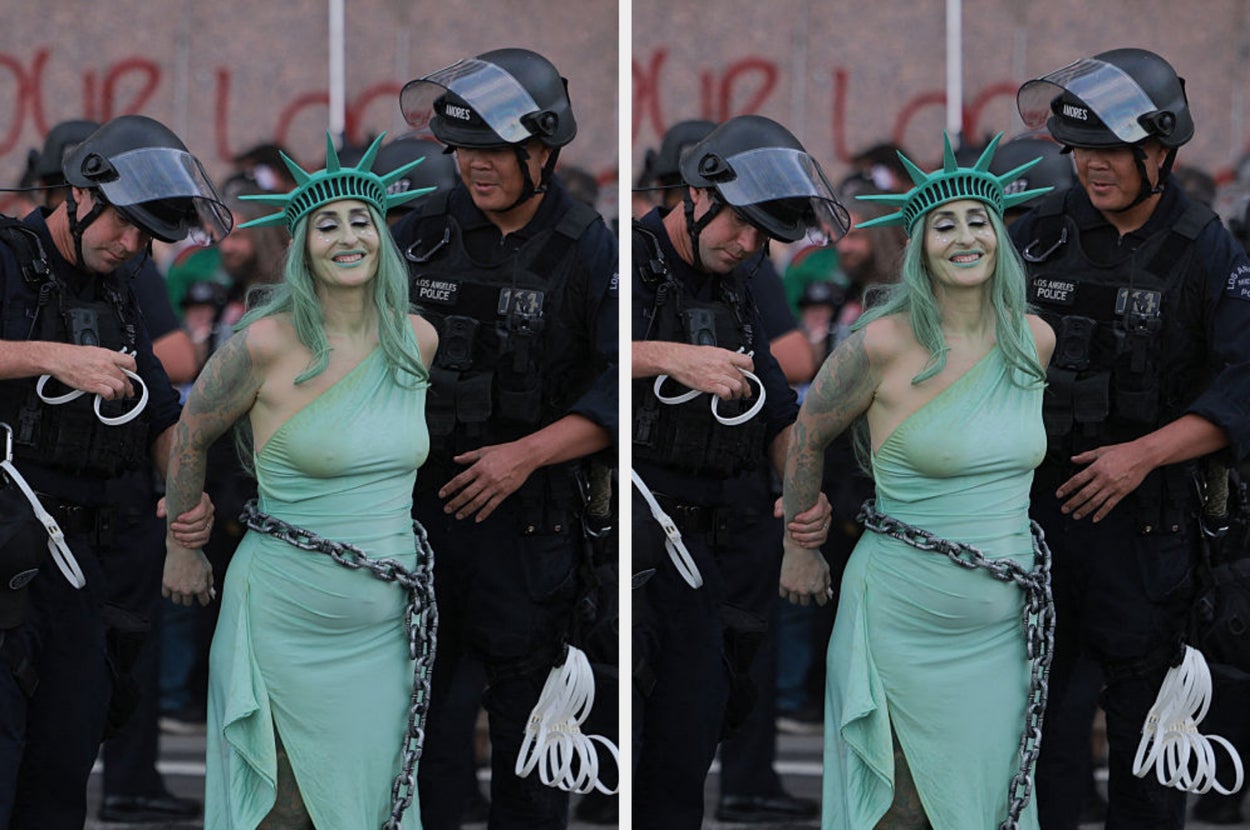 Person dressed as Statue of Liberty being detained by officers wearing protective gear