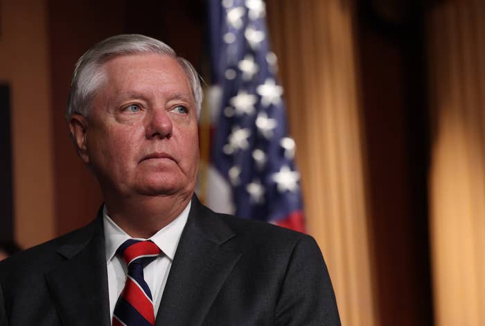 A antheral   successful  a suit   and striped necktie  stands successful  beforehand   of an American flag, looking thoughtful, successful  a quality    setting