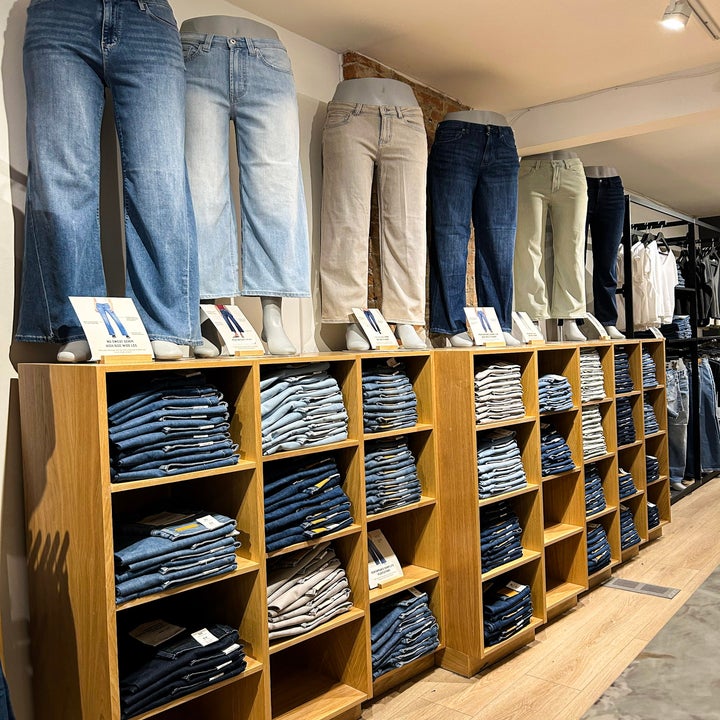 Mannequins display various styles of jeans above neatly stacked shelves in a retail store