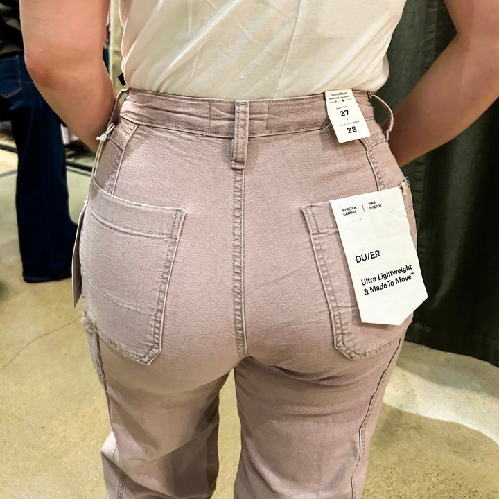 Person wearing fitted pants with visible tags at the back, suggesting they are considering or trying on the clothing for a potential purchase