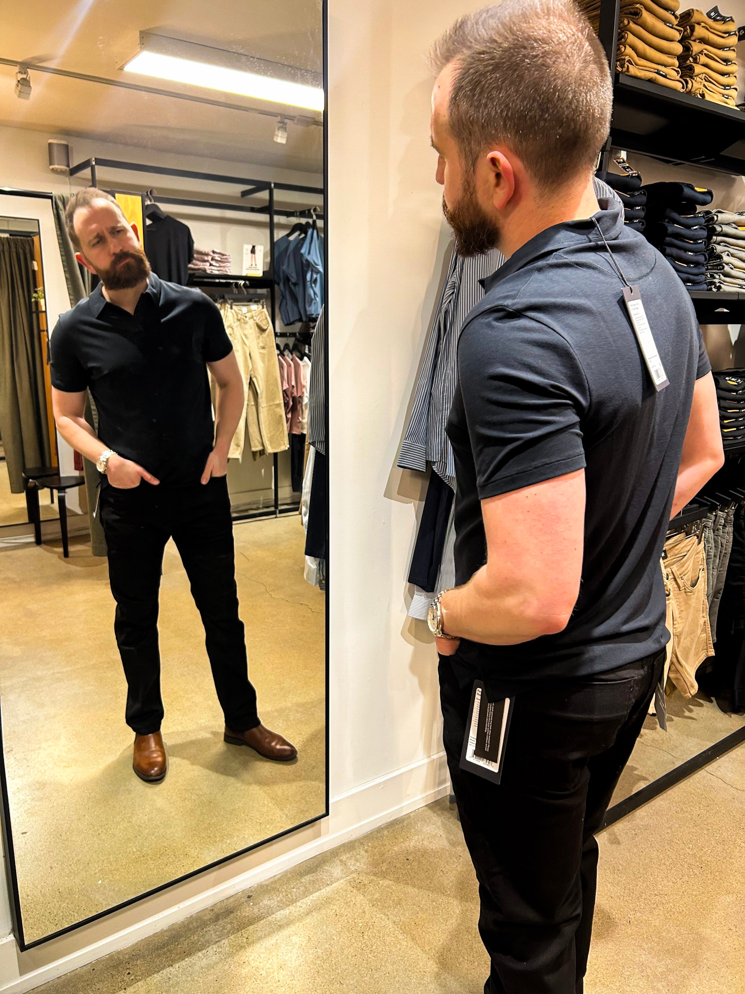 Man trying connected  casual apparel  successful  a store, looking into a mirror. Clothing tags are visible, suggesting fitting oregon  shopping