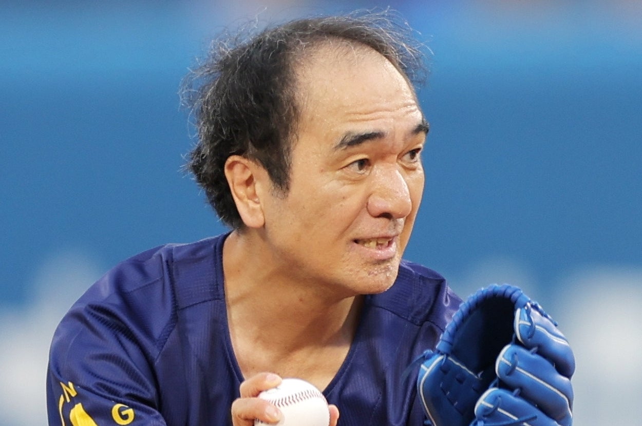 男性が野球ボールを持ち、グローブをはめている。集中した表情。球場での一場面。