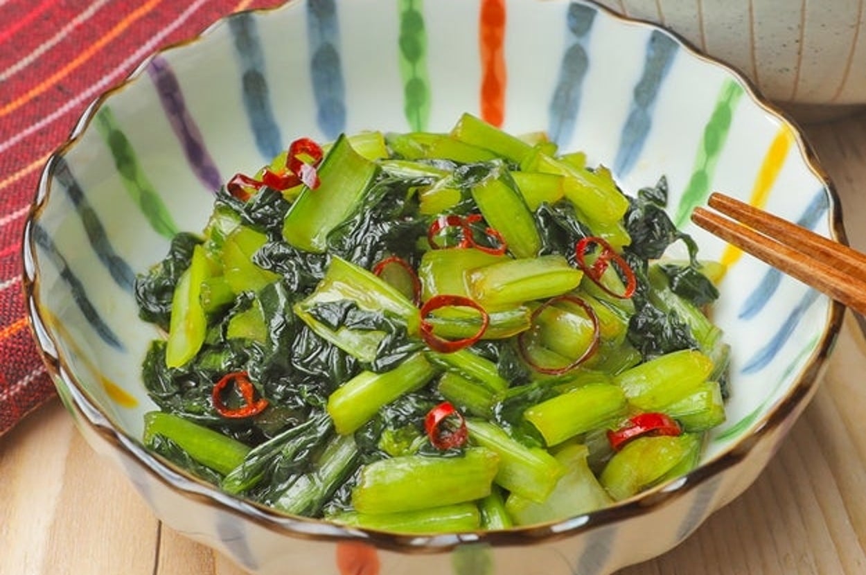 ボウルに盛られた青菜と赤唐辛子の炒め物が、白ご飯と一緒に並んでいる。