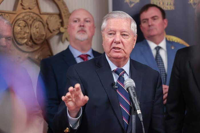A antheral   successful  a suit   speaks astatine  a podium, surrounded by different   men successful  suits, during a property   event