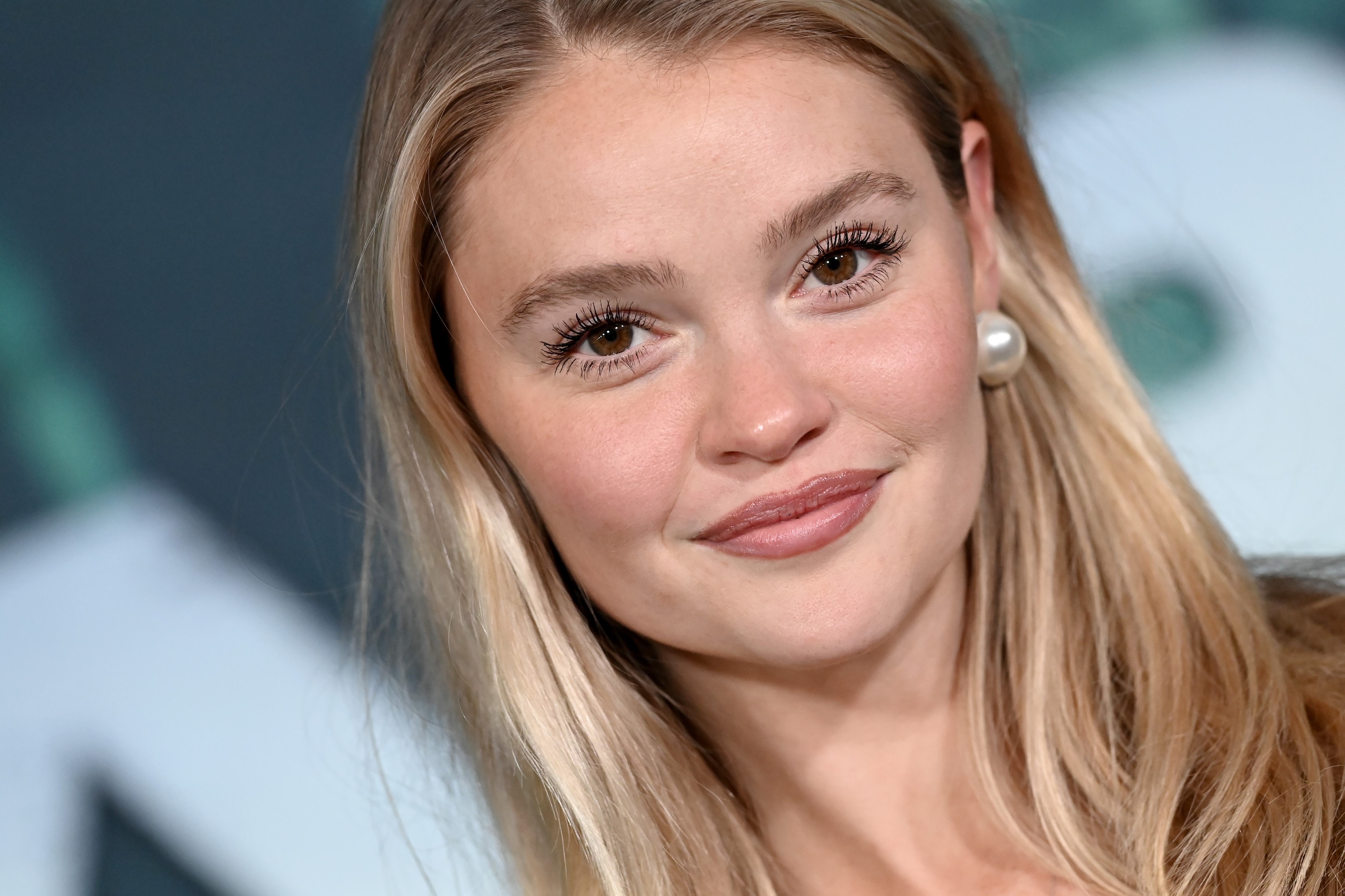 Person smiling astatine the camera with agelong hair, wearing pearl earrings