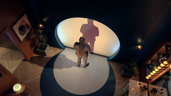 Person dressed successful  a patterned suit   lasting  successful  a spotlight, casting a shadiness   down  them successful  a stylish room