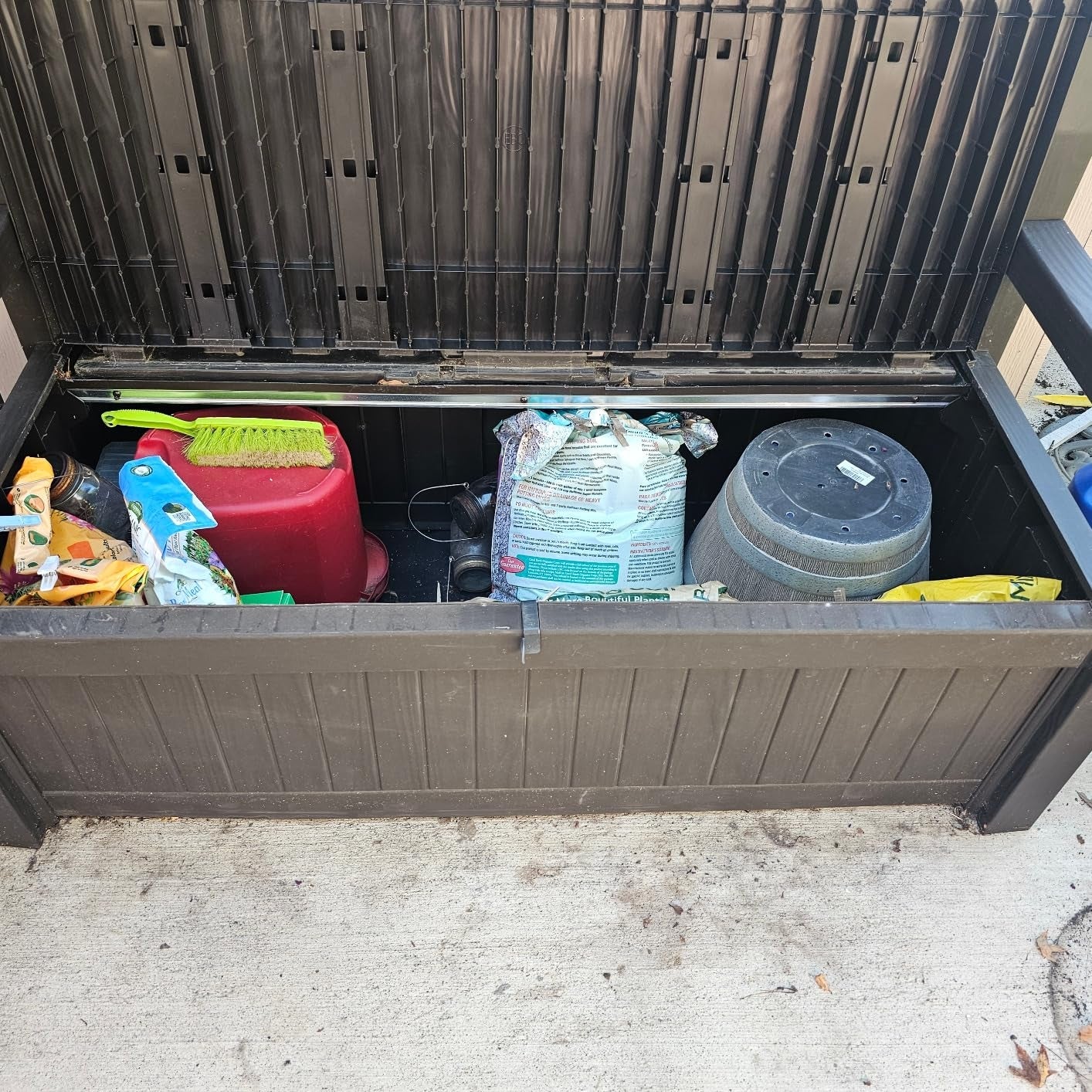 Storage container  with plot  tools, ungraded   bags, and a compost bin, suitable for organizing outdoor supplies