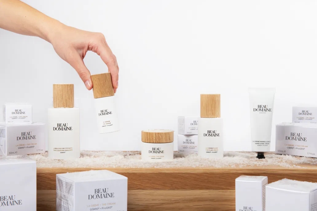 Person arranging Beau Domaine skincare products connected  a woody  shelf; products diagnostic   woody  caps