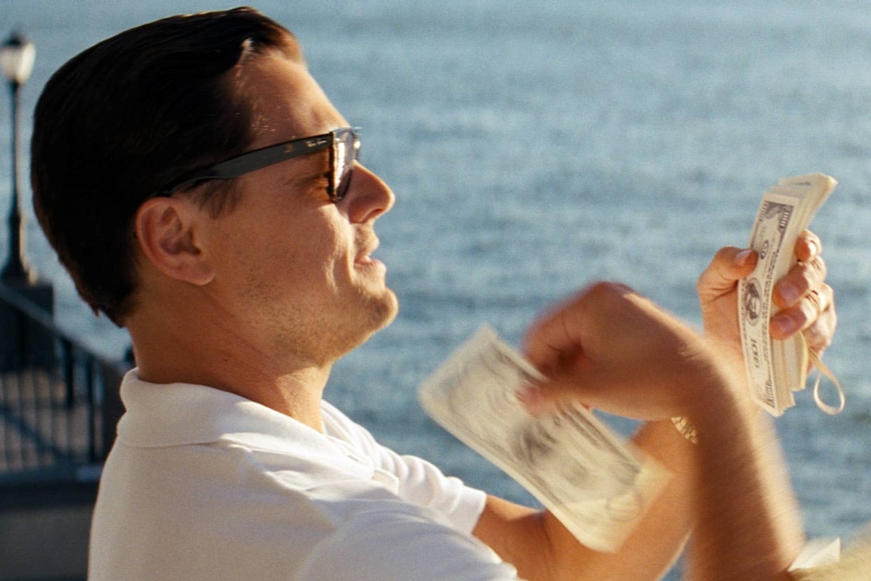Image of Leonardo DiCaprio throwing money while standing by the water