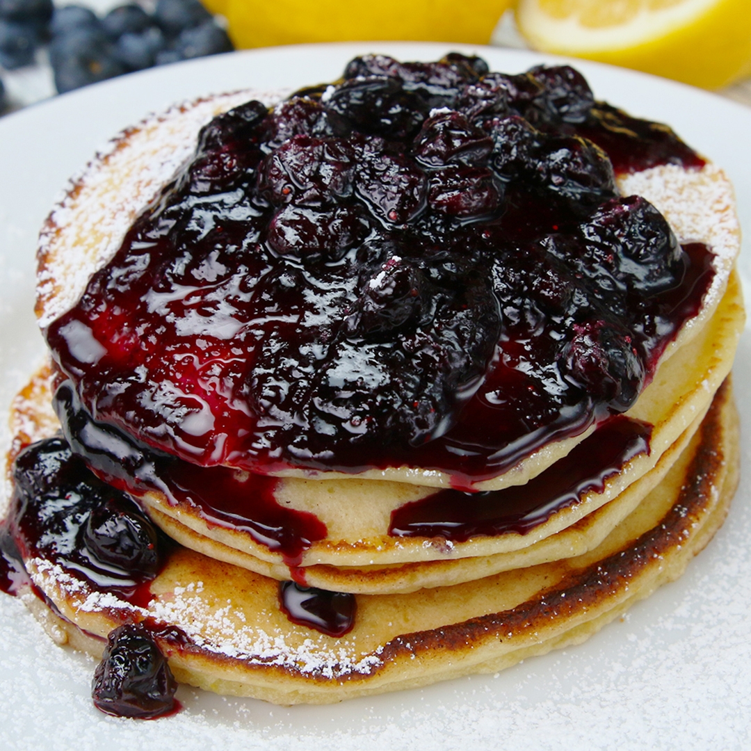 Stack of pancakes topped with a generous serving of blueberry compote connected a plate