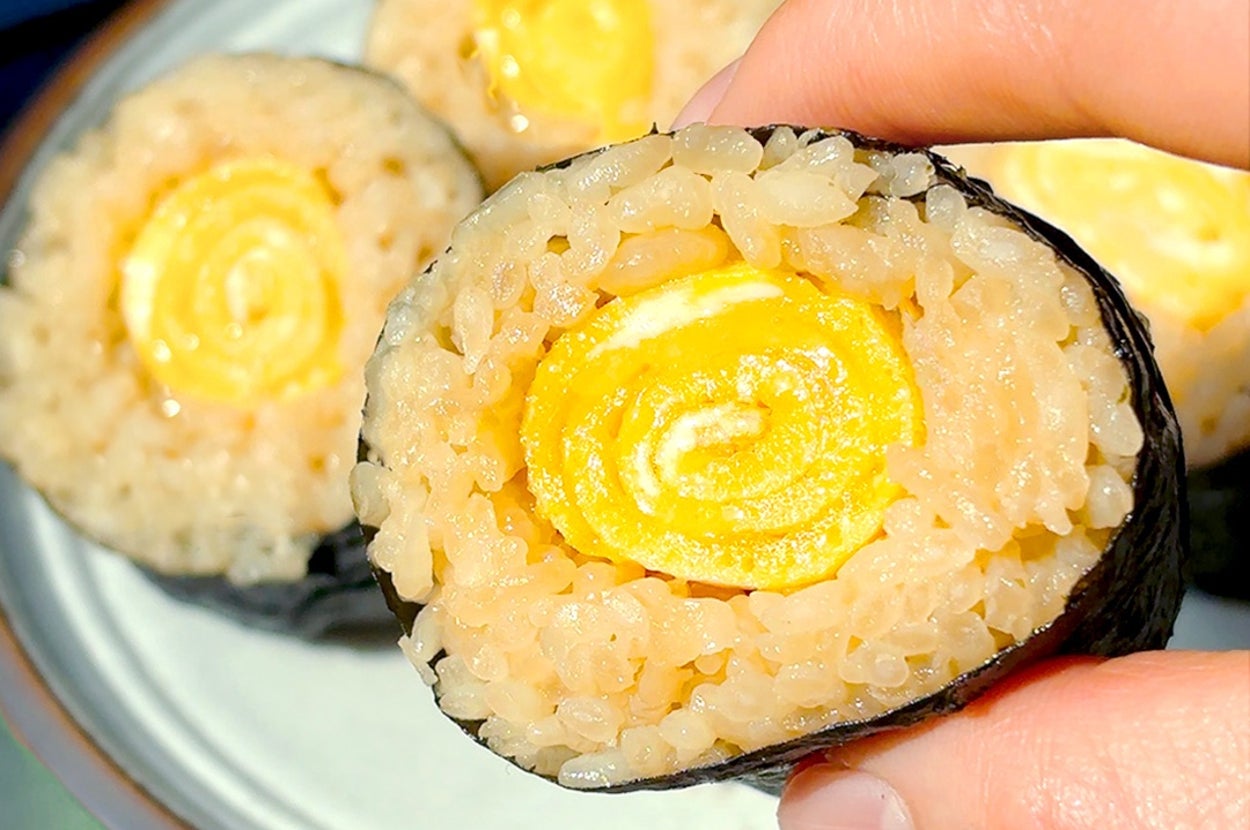 手で持った卵巻き寿司のクローズアップ。