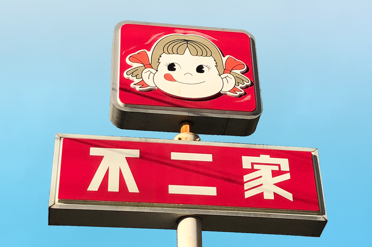 赤い看板に描かれた女の子の顔と「不二家」の文字。