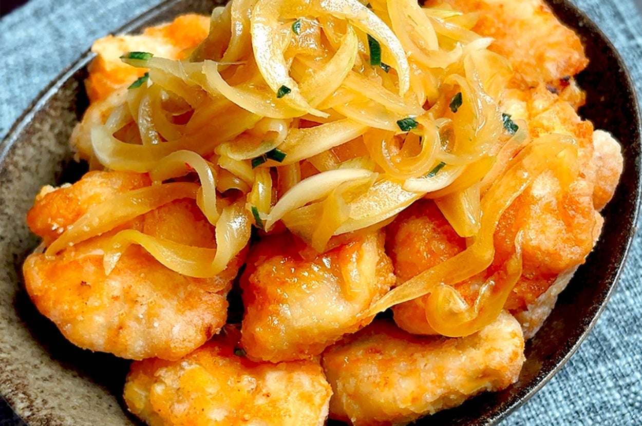 鶏肉のから揚げに、玉ねぎがたっぷりのった料理が陶器の器に盛り付けられている。