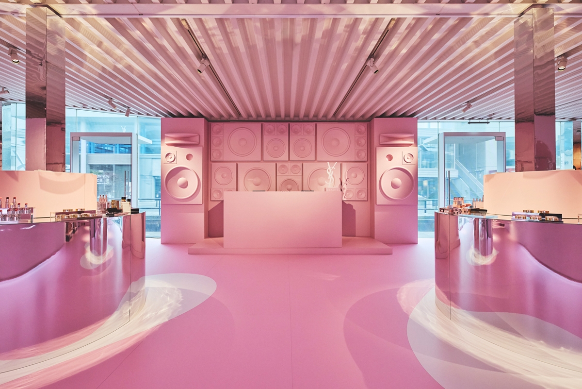 ピンクのテーマで装飾されたポップアップストアの室内、音響設備と化粧品ディスプレイが配置されている。