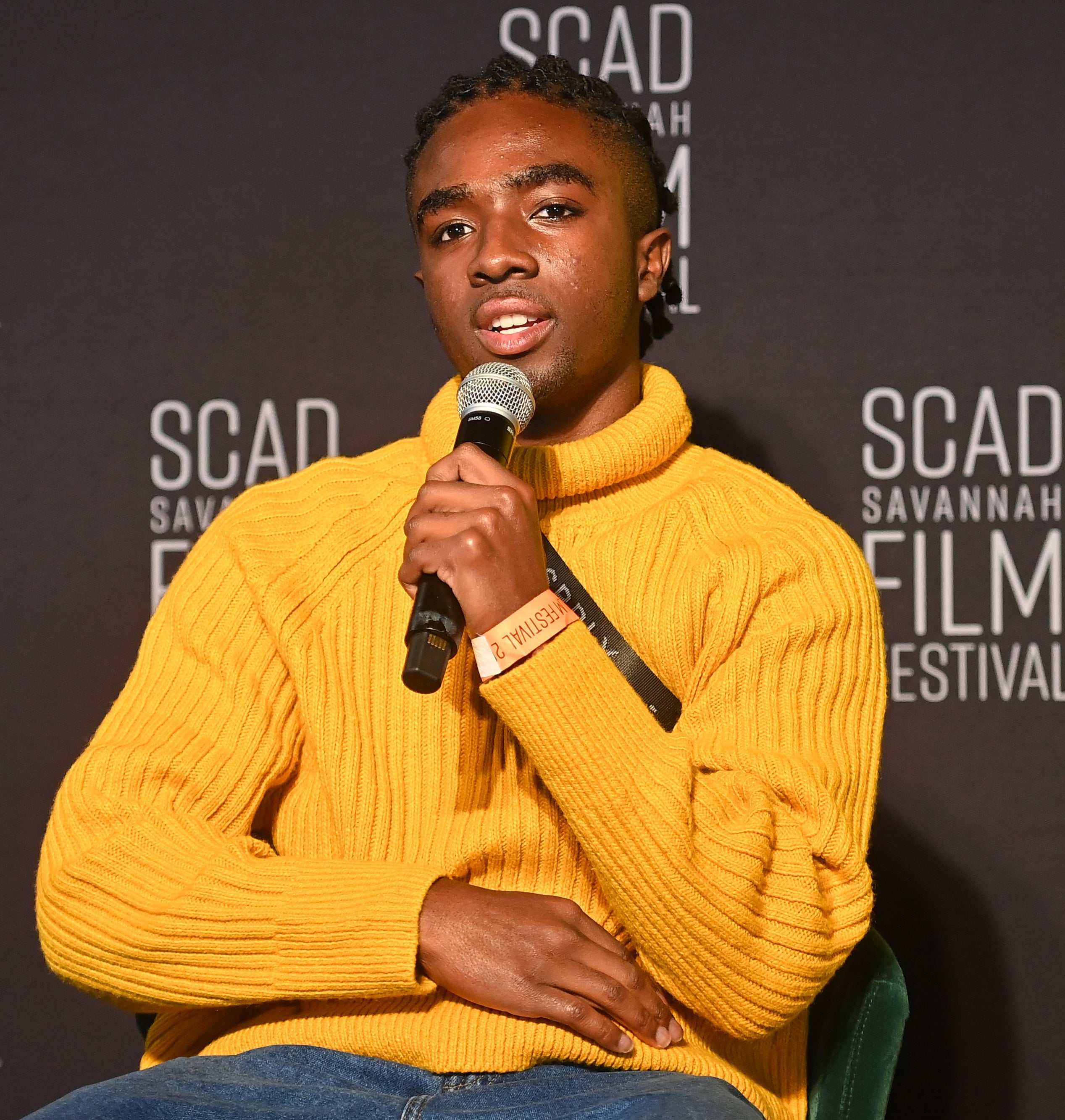 Caleb speaking into a microphone at an event