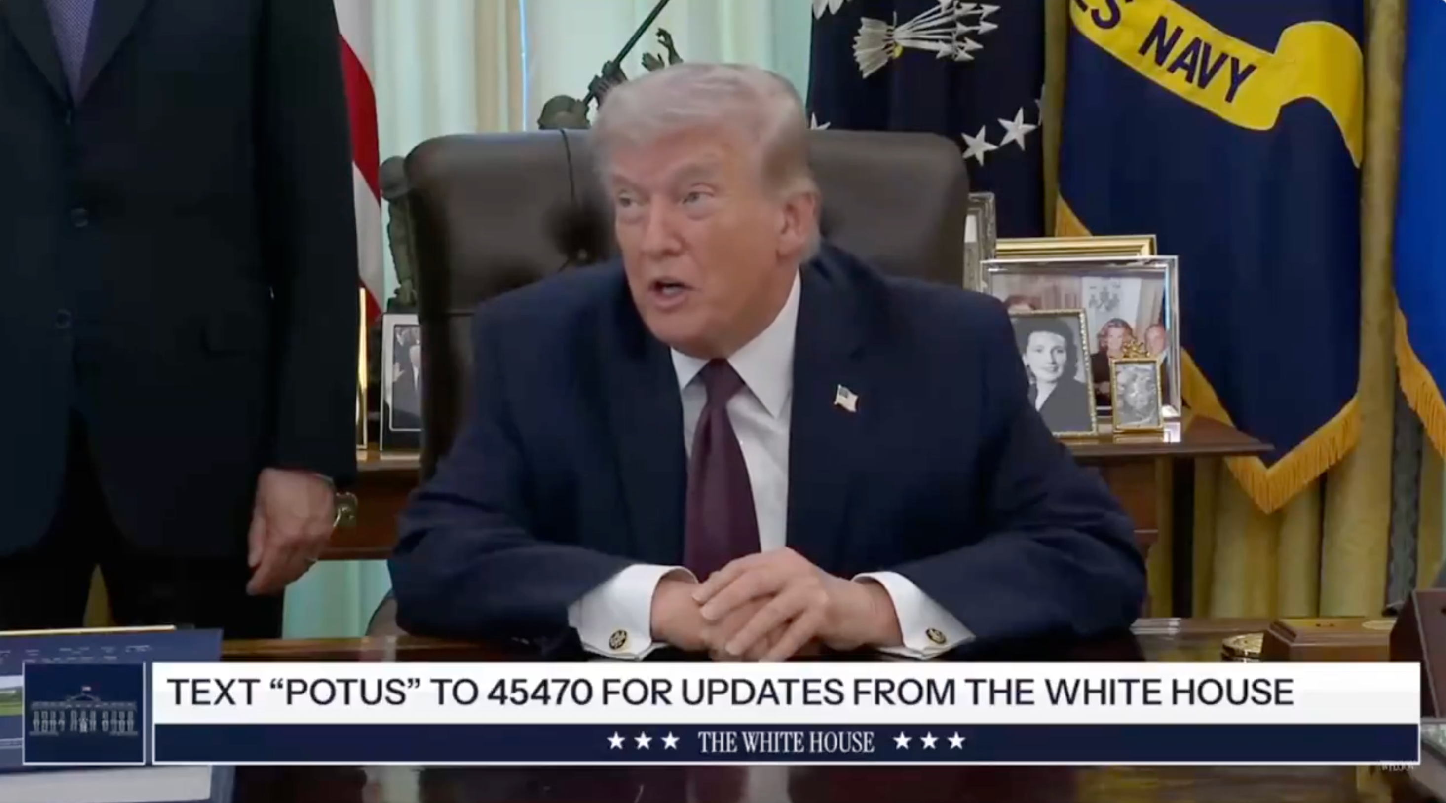 A idiosyncratic sits astatine a table with framed photos and flags behind. Text astatine bottommost reads "Text 'POTUS' to 45470 for updates from the White House."