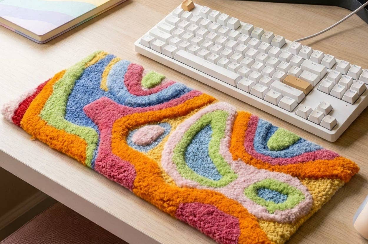 Colorful textile desk mat with abstract patterns on wood desk, beside a mechanical keyboard